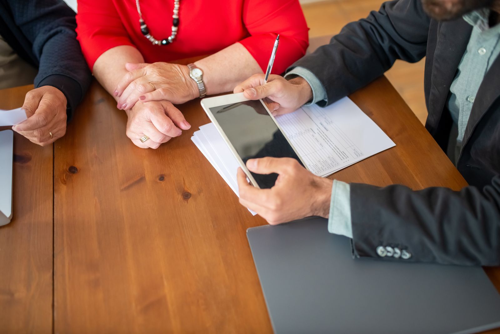 Mains tenant une tablette tactile et un stylet pour signer un document en réunion
